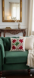 Embroidered floral pillow with red and green leaves on green velvet sofa, cozy living room decor