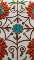 Vibrant floral embroidery with turquoise, red, and brown threads on white fabric, perfect for home decor.