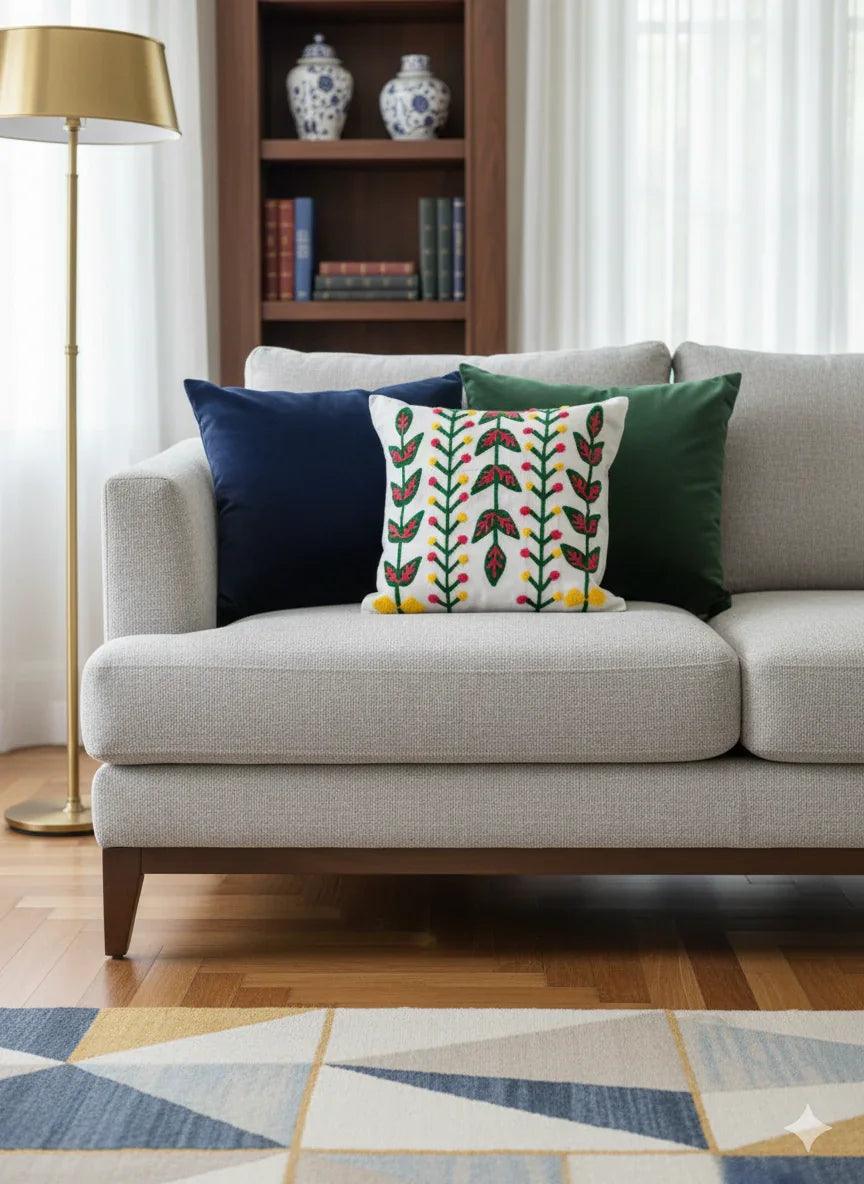 Floral embroidered throw pillow on gray sofa with blue and green cushions, modern living room decor