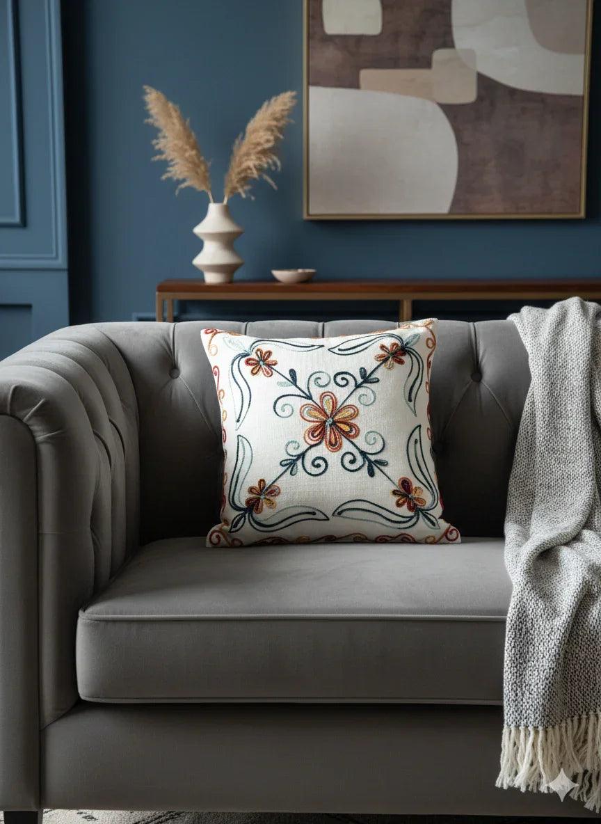 Embroidered floral throw pillow with orange and teal blooms on cream linen, perfect for cozy home decor.