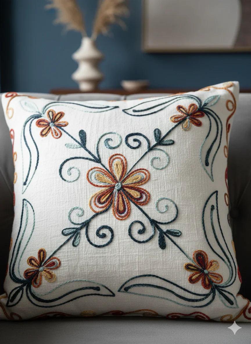 Embroidered floral throw pillow with orange and teal blooms on cream linen, perfect for cozy home decor.