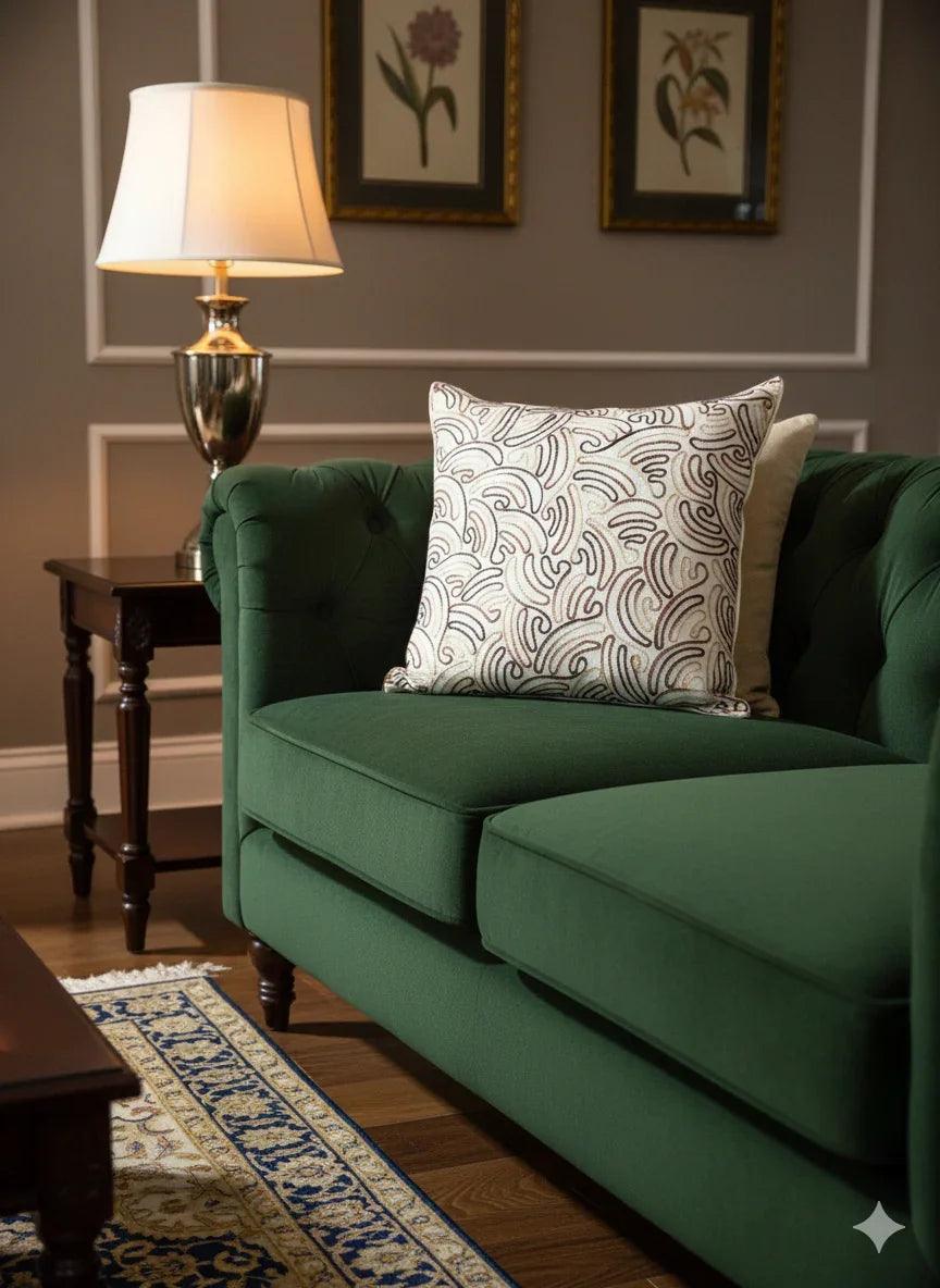 Green tufted sofa with patterned throw pillow, side table, and lamp in cozy living room