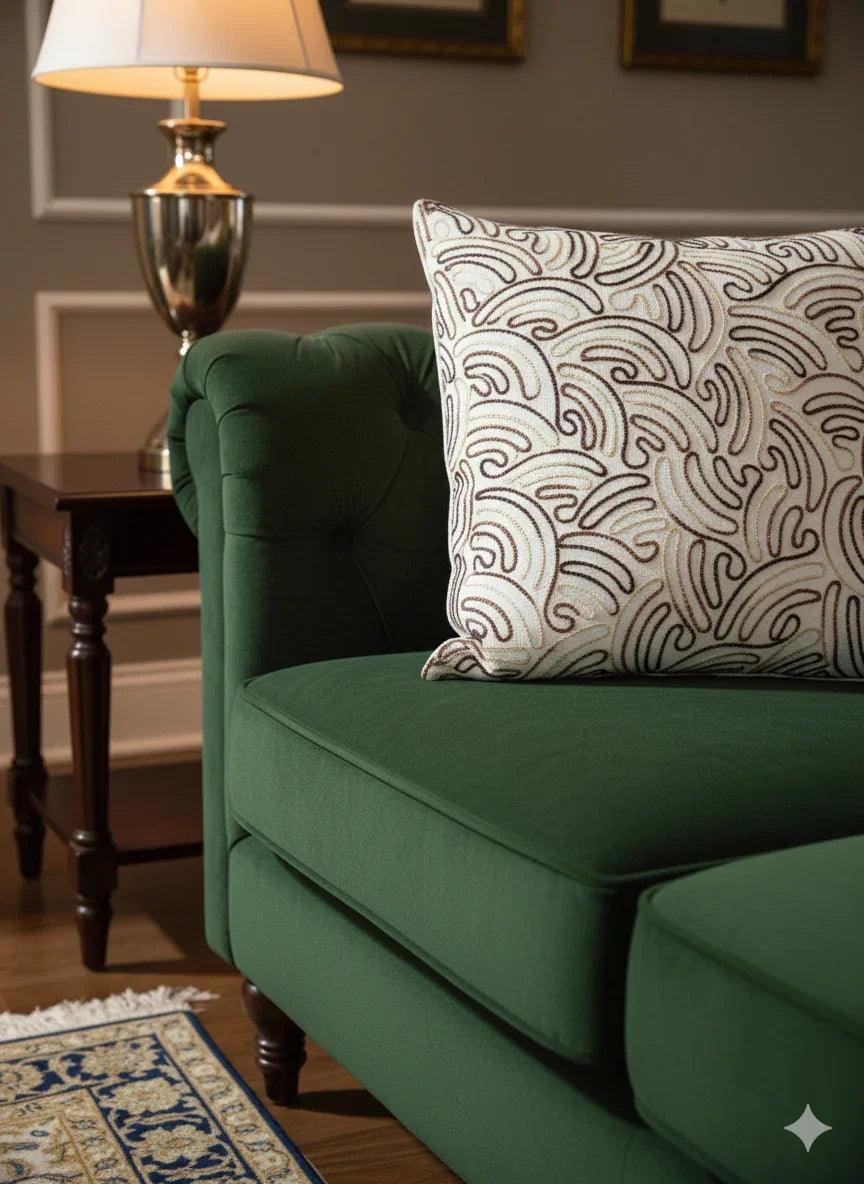 Green tufted sofa with patterned throw pillow, side table, and lamp in cozy living room