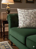 Green tufted sofa with patterned throw pillow, side table, and lamp in cozy living room