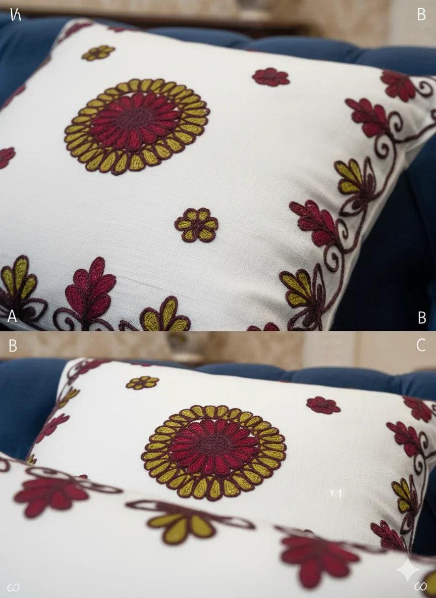 White floral embroidered cushion on blue velvet sofa, decorative home accent with red and gold motifs
