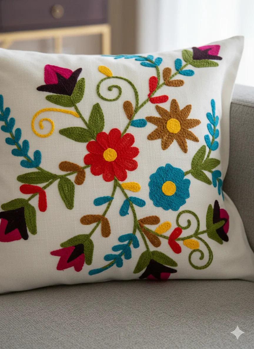 Colorful floral embroidered throw pillow on gray sofa, boho home decor accent