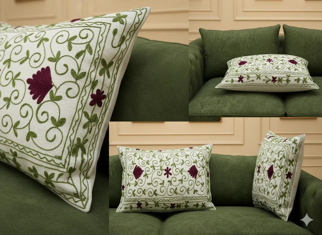 Embroidered floral throw pillow with green vines and burgundy flowers on cream fabric, styled on green sofa