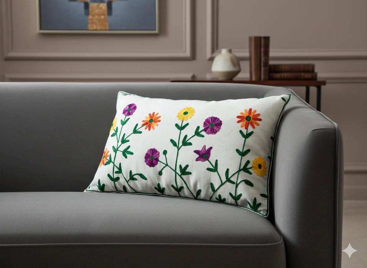 White floral embroidered pillow with colorful daisies on gray sofa, home decor accent