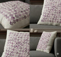 White throw pillow with purple swirl embroidery, styled on gray sofa for cozy home decor